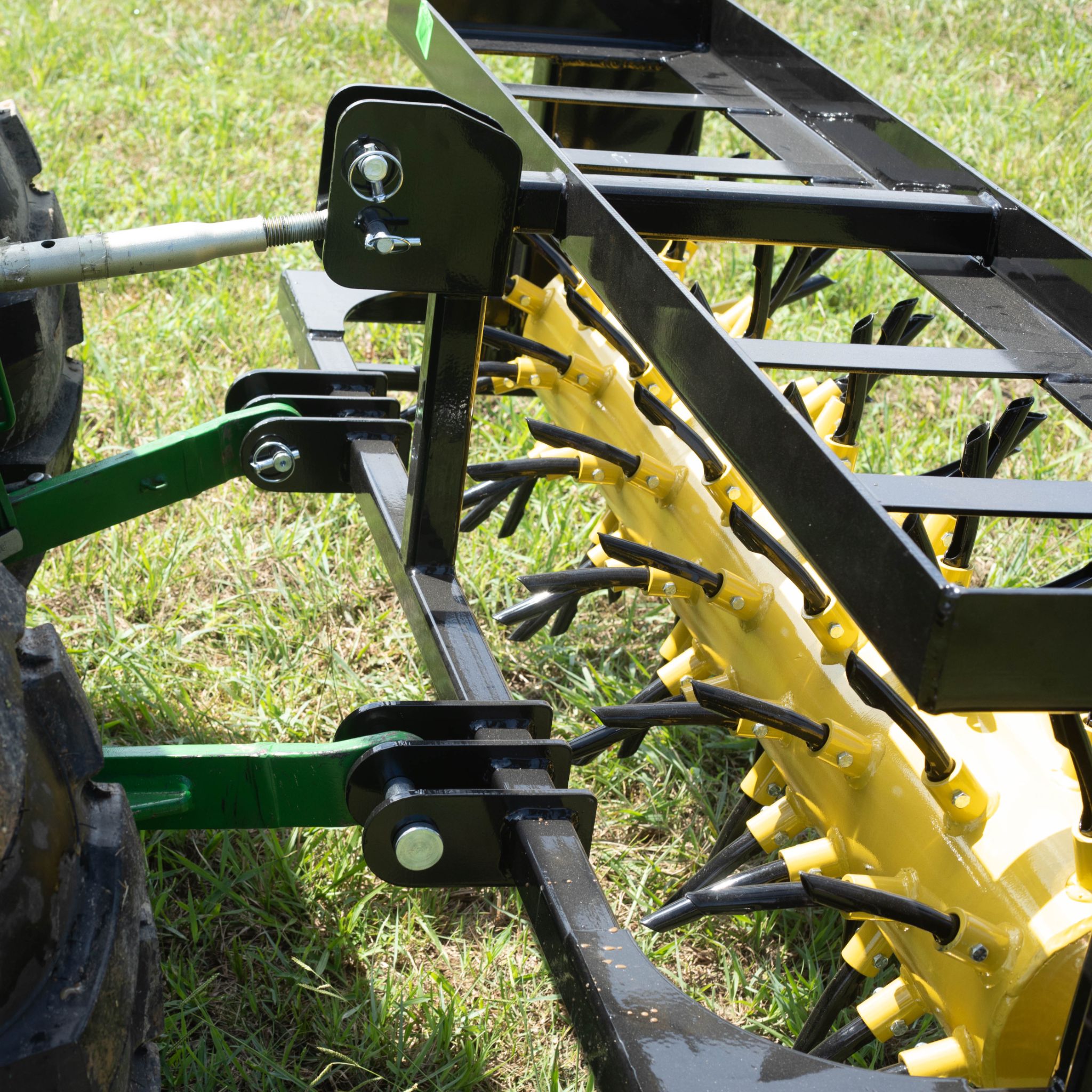 Tractor carrying a Drum Plug Aerator  in the field