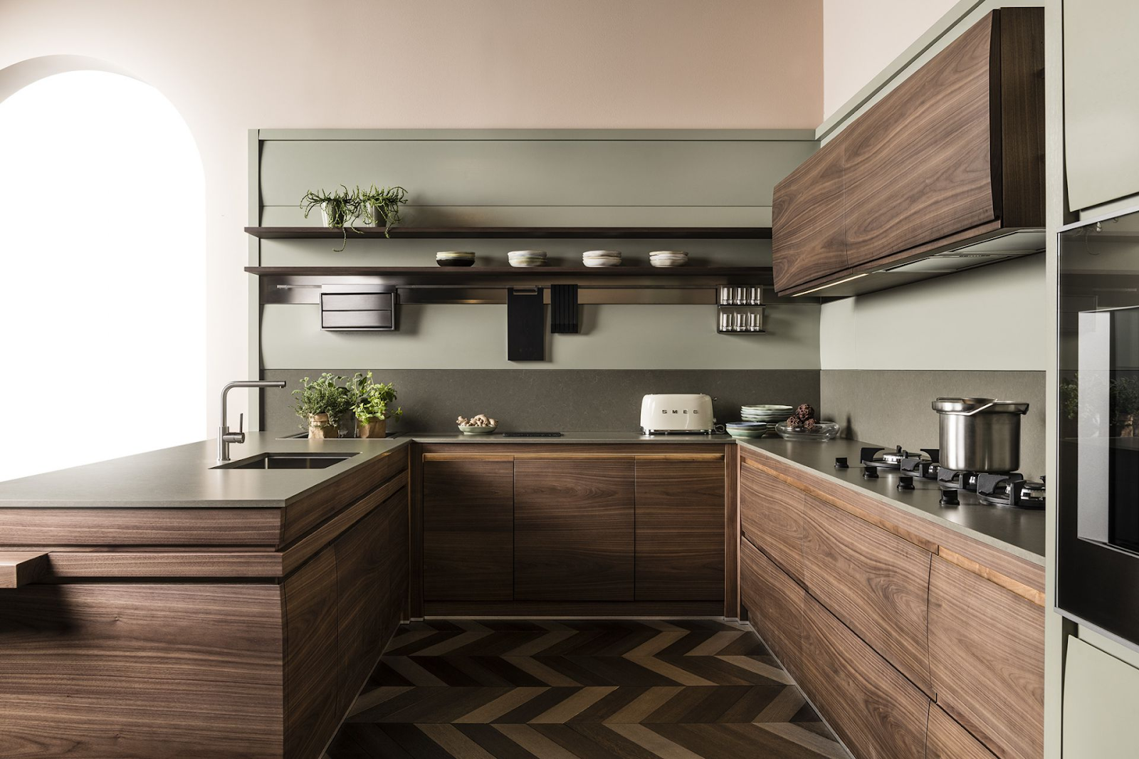 modern small u-shaped kitchen with stained wood cabinets, herringbone flooring and natural green backsplash. open shelves keep the space feeling open and modern finishes give it an updated look