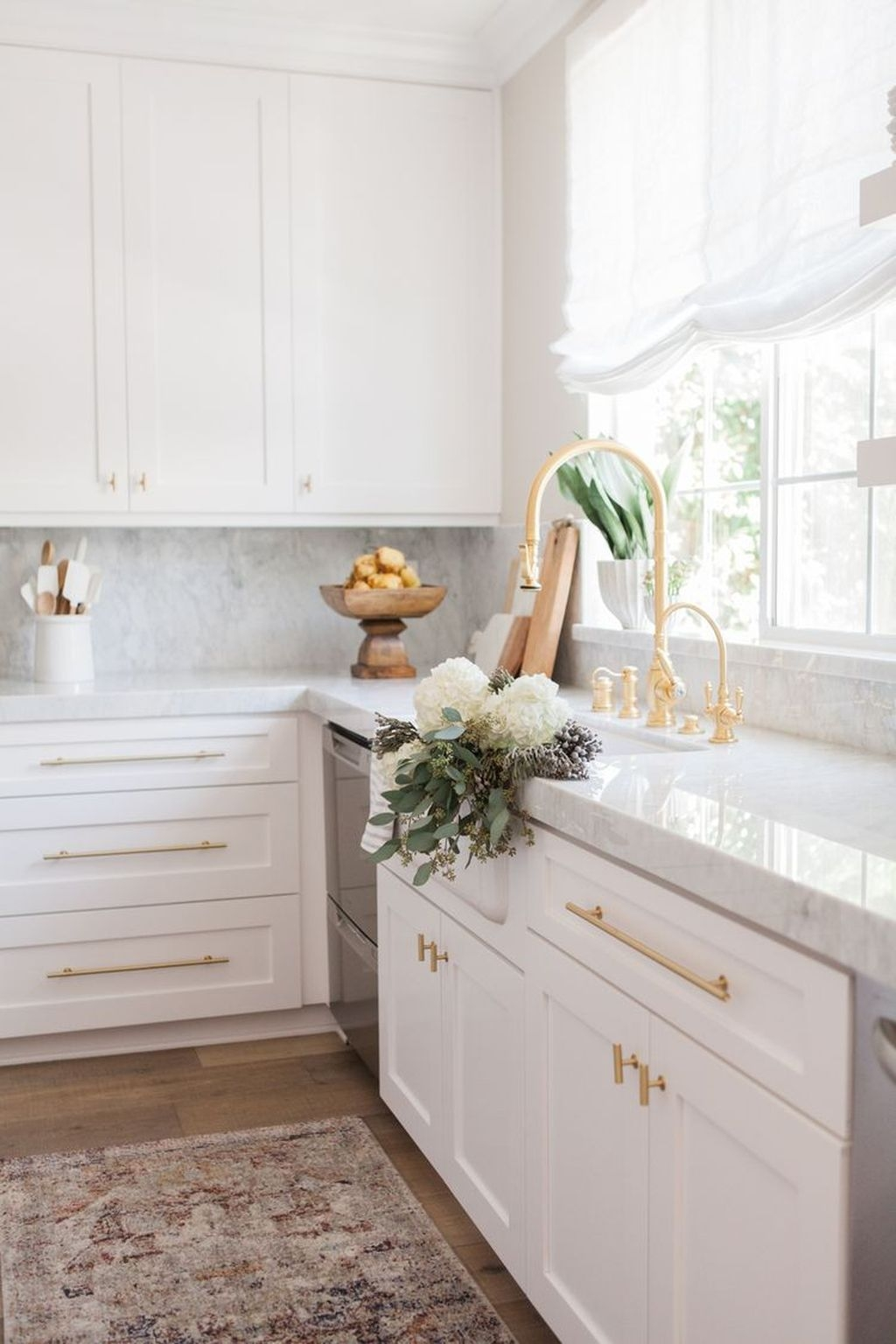 contemporary white and gold kitchen design with white shaker cabinets, brass bar pulls and brass kitchen sink faucet