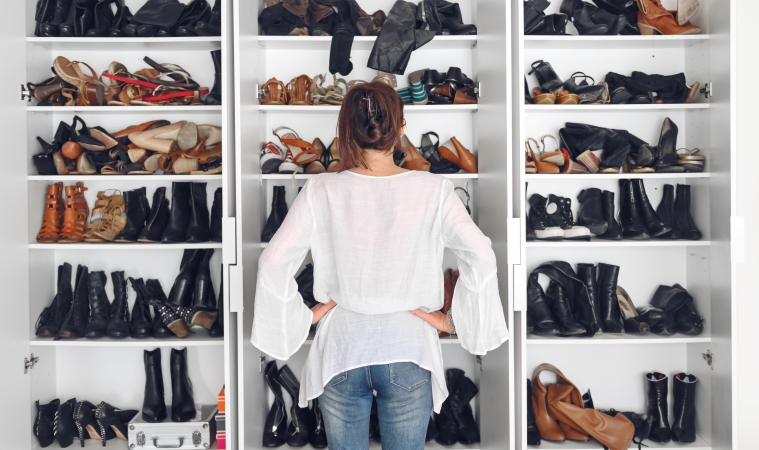 A woman examines her shoe collection, deciding what should stay and what should go.