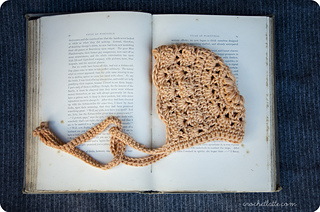 apricot baby bonnet lying on vintage book