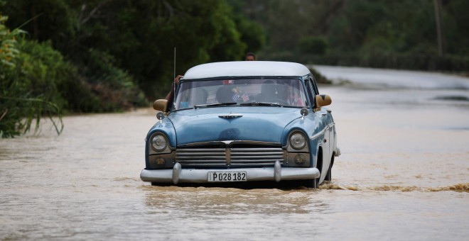 Un coche circula por una carretera inundada de Guantánamo tras el paso del huracán Matthew. / ALEXANDRE MENEGHINI (REUTERS)