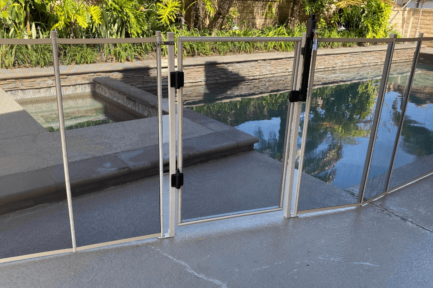 White mesh removable pool fence gate installed around a swimming pool
