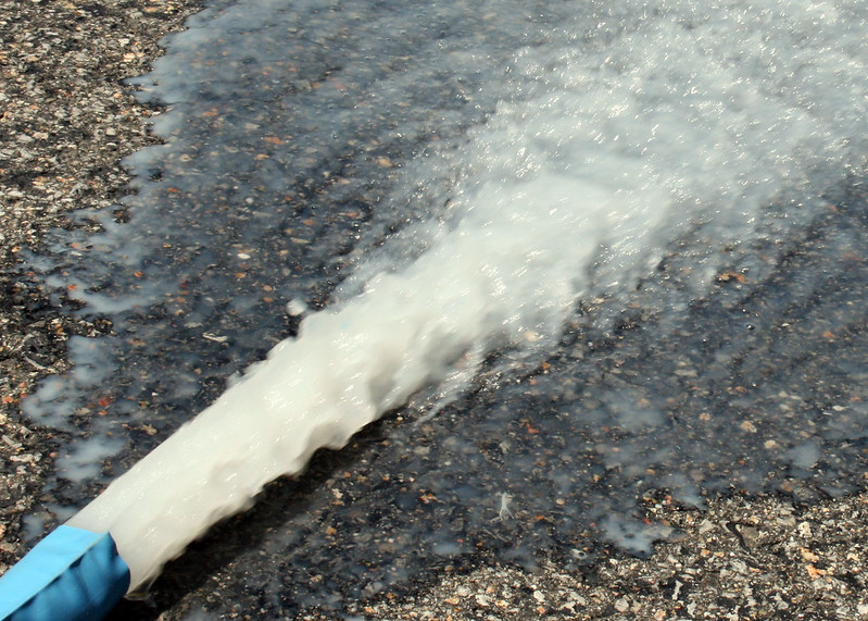 a pool filter hose backwashing water onto concrete 