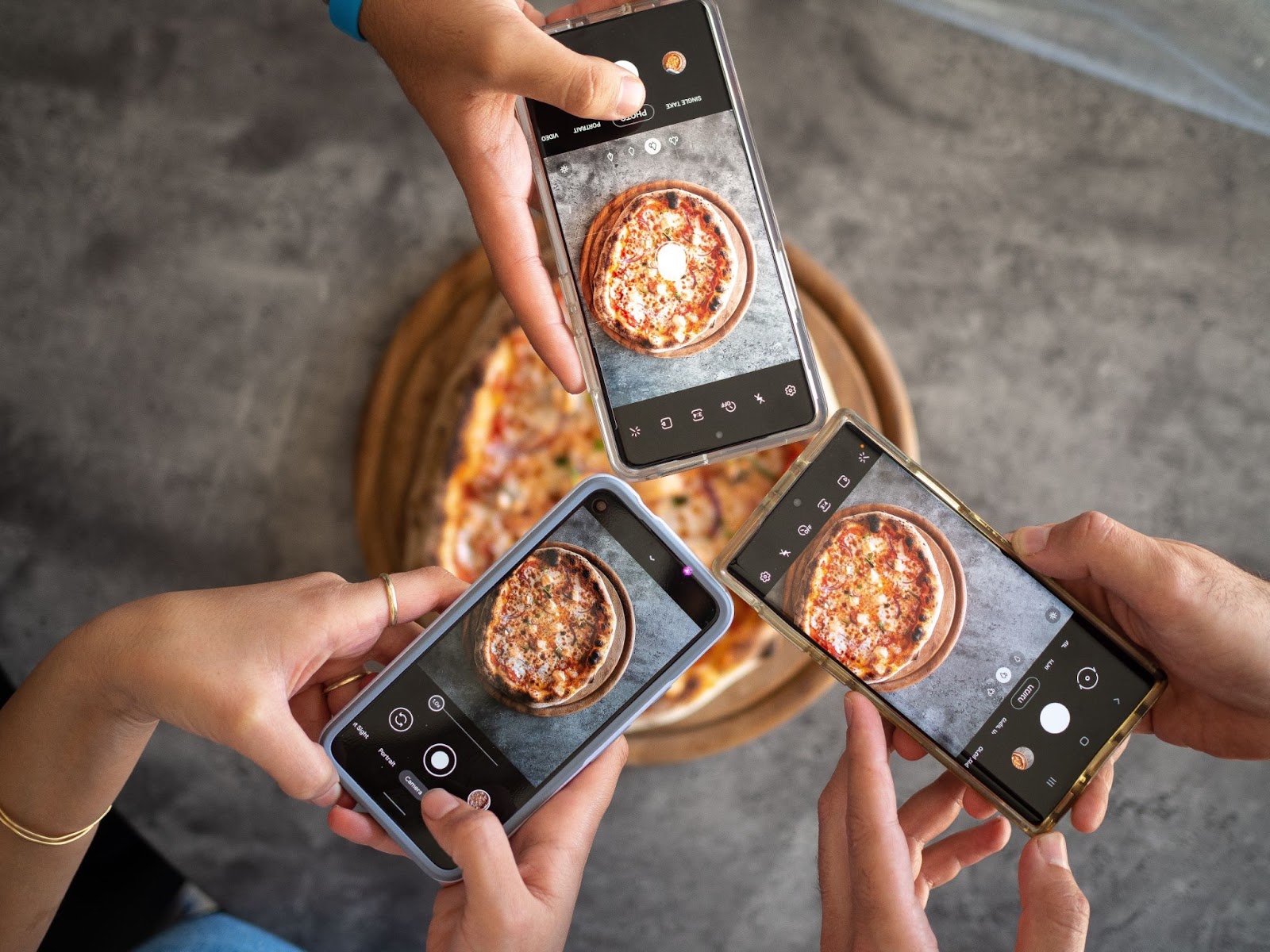a top down view of three smart phone cameras taking a picture of a pizza