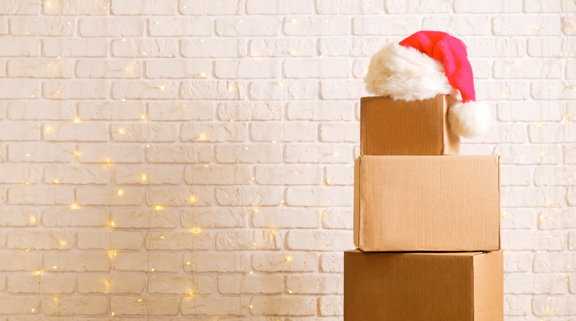 Three boxes stacked together with organized Christmas decorations in them and a Santa hat on top