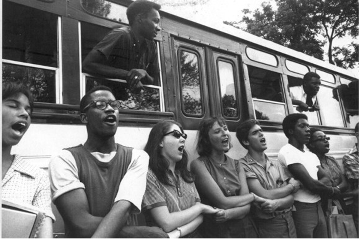 Freedom Summer volunteers holding hands and singing Freedom Songs in front of bus as they prepare to depart to Mississippi.