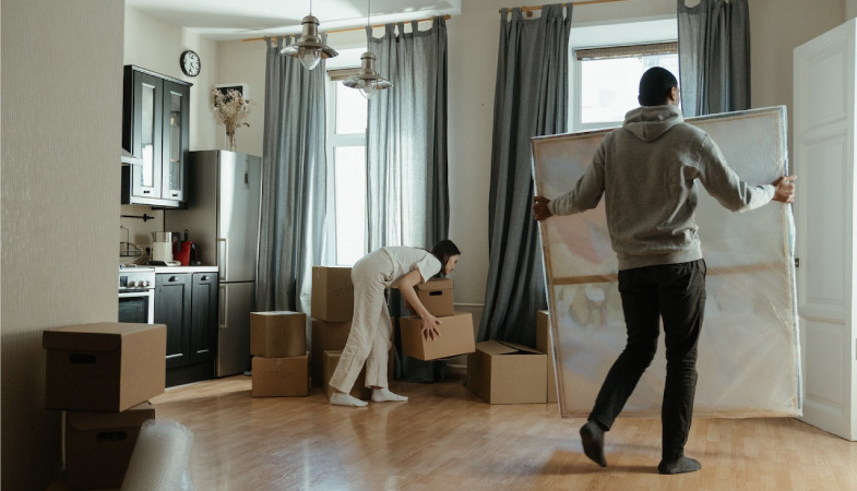 A couple carrying artwork and boxes out of their home while moving to Philadelphia from NYC.