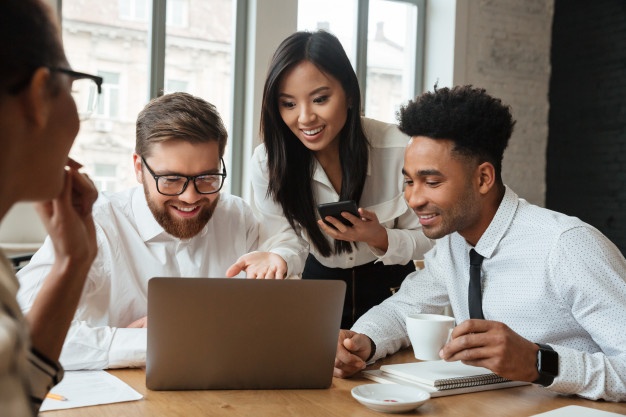 Cheerful successful young colleagues using laptop computer