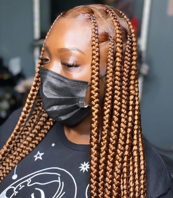 Lady on mask shoes off her honey-colored  large knotless braids