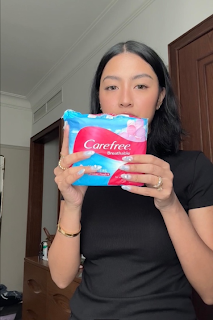 A person holding a package of sanitary pads

Description automatically generated