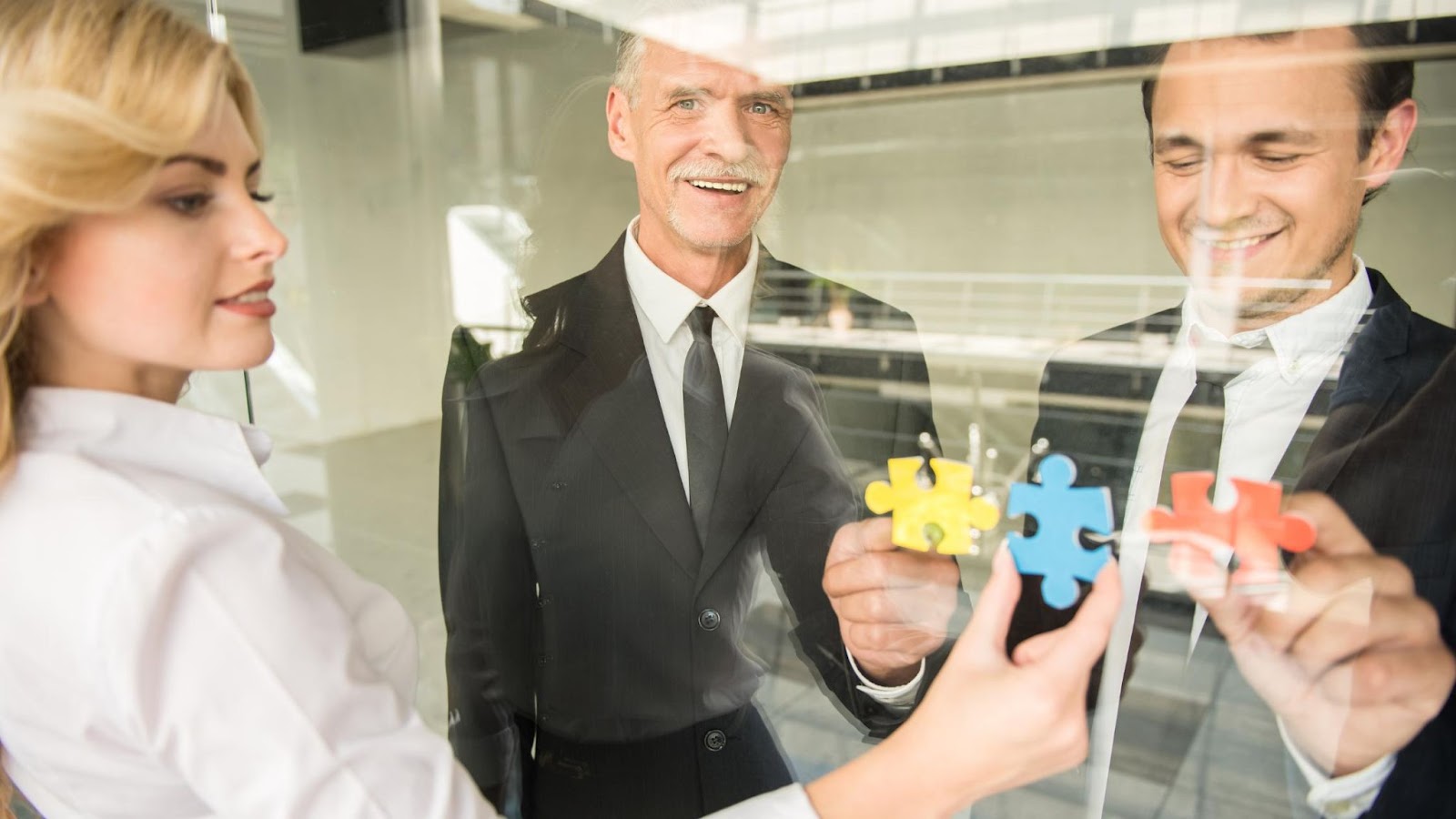 Three people completing a puzzle, to show a call center outsourcing partnership. 