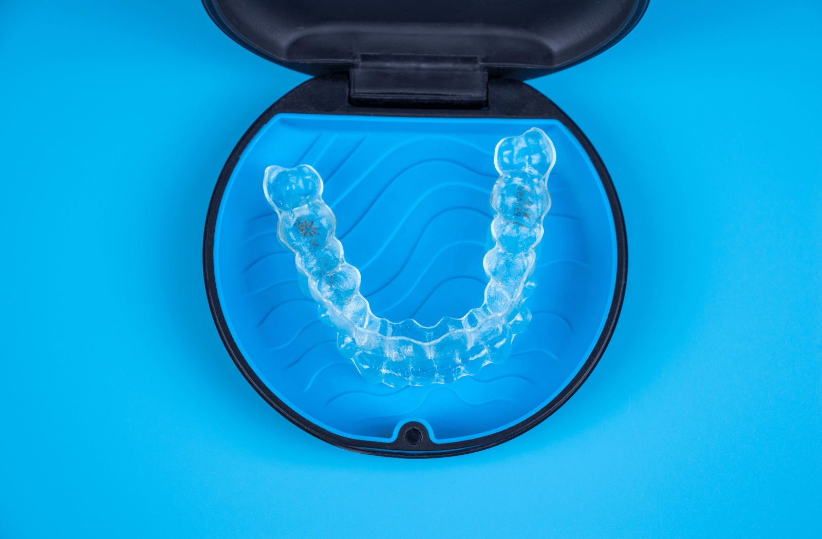 A blue and black protective case containing two Invisalign aligners.